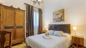 A bedroom with a large bed, wooden wardrobe, and a nightstand with a lamp. - Vacation Apartment 'Casa Tesalia' with Sea View, Wi-Fi and Air Conditioning (Güímar)