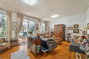 Un salón amplio con sofá, sillón, aparador de madera y estantería.