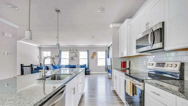A modern kitchen with a central island, stainless steel appliances, and a view to the living area. - Sea Oaks Village 12442 #5 (Berlin)