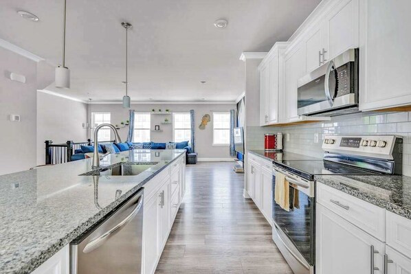 A modern kitchen with a central island, stainless steel appliances, and a view to the living area.