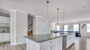 A spacious kitchen with white cabinetry, a granite countertop, and pendant lighting. - Sea Oaks Village 12442 #5 (Berlin)