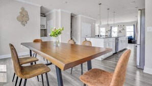 A modern kitchen with white cabinets, a wooden dining table, and a vase of flowers. - Sea Oaks Village 12442 #5 (Berlin)