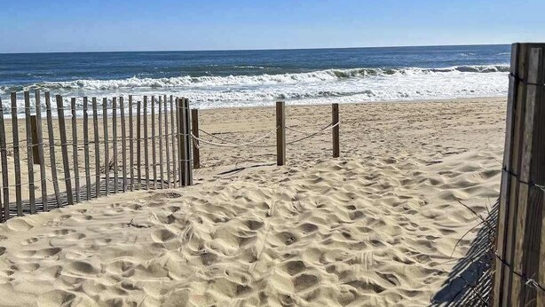 A sandy beach with a wooden fence and a view of the ocean. - Bluewater East 501N (Ocean City)