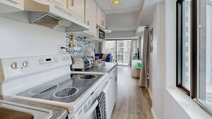 A modern kitchen with a built-in stove, microwave, and oven. There is a window on the right side providing natural light. - Bluewater East 501N (Ocean City)