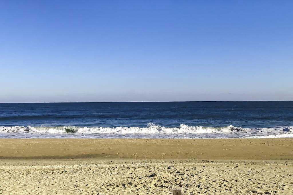 A beach with waves, clear sky, and a sandy shore.