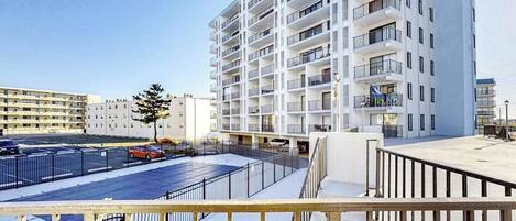 Un hôtel à plusieurs étages, doté de balcons, d’un parking et offrant une vue sur un ciel dégagé.