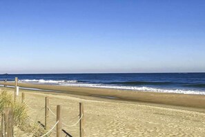 Ein Strand mit einer Holzlattenveranda und blauem Himmel.