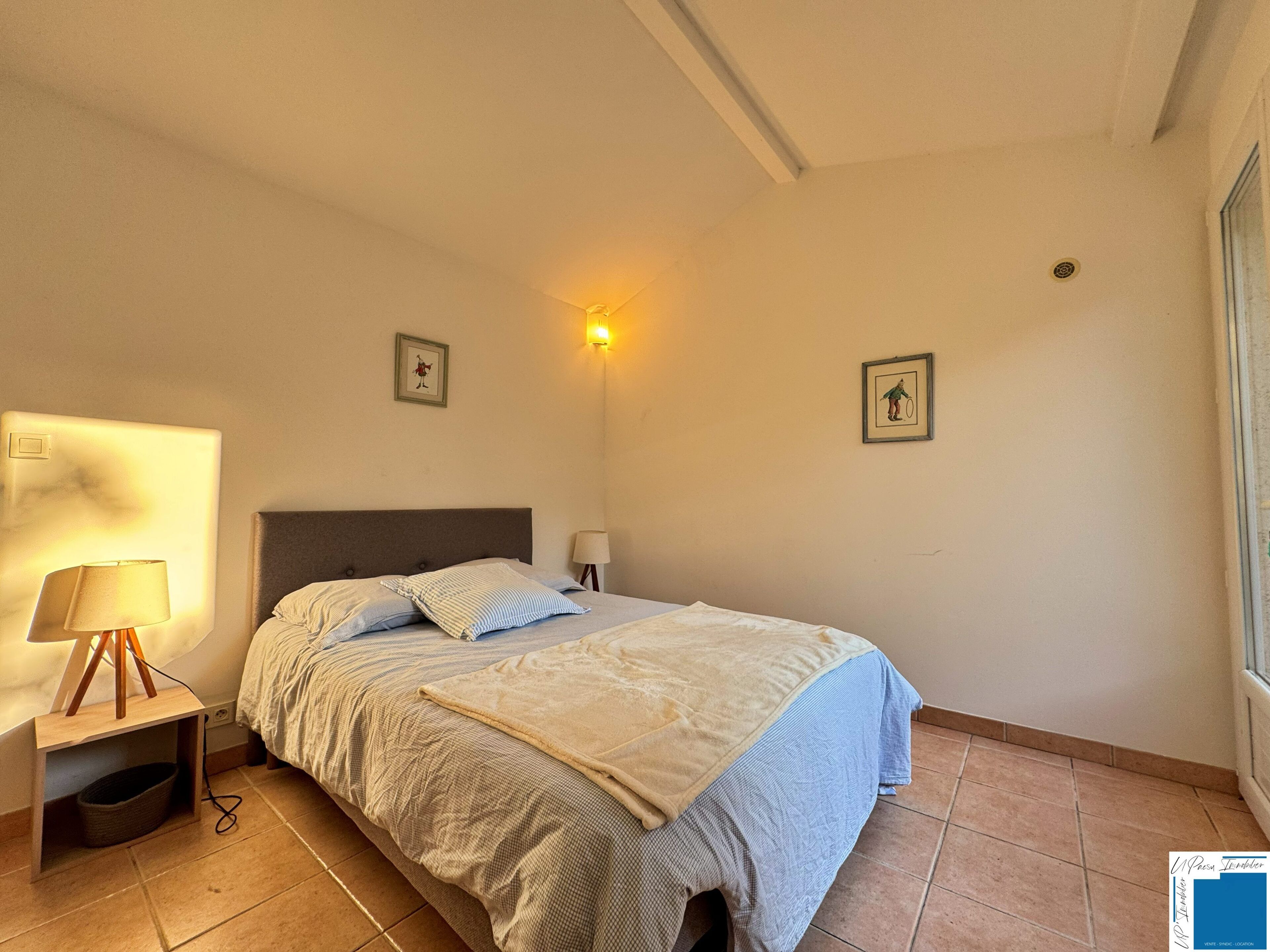 Una camera da letto con un letto, lampade sui comodini, una luce a parete e un quadro incorniciato.