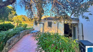 A patio with a stone wall, a small table, and chairs. - Villa Caroubier - A peaceful stay just a stone's throw from the sea (Zonza)