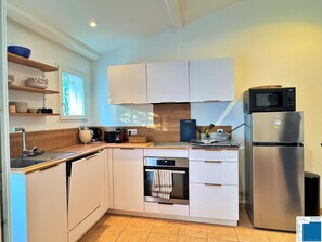 Eine moderne Küche mit weißen Schränken, einem eingebauten Backofen, einer Mikrowelle und einem Edelstahl-Kühlschrank.