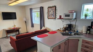 A compact kitchen with a sofa, a TV, a microwave, and a sink.