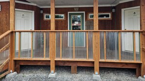 A wooden balcony with a metal railing, a concrete ceiling, and doors labeled 'Suite A' and 'Suite B'. - The Queen Mini Suite B (Craig)