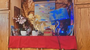 A wooden cabinet with a red cloth, a clock, books, and decorative items. - Magic ArtHouse at the heart of Las Vegas 
Near everything (North Las Vegas)