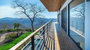 Un bâtiment moderne doté d’une terrasse en bois, de grandes fenêtres et offrant une vue sur les montagnes.