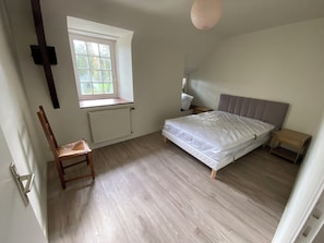 Une chambre à coucher comprenant un lit, une chaise, une fenêtre, un radiateur et une table de chevet.