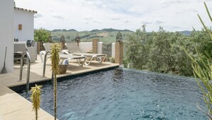 Una piscina con lettini e vista sulla campagna.