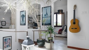 Un interno moderno con una scala, piante in vaso, una chitarra e opere d'arte incorniciate alle pareti.
