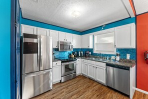 Eine moderne Küche mit Edelstahlgeräten, weißen Schränken und einer blauen Akzentwand.