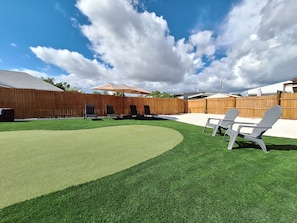 A backyard with artificial grass, a wooden fence, and outdoor furniture.