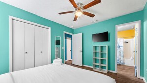 A bedroom with a bed, a ceiling fan, a TV, and a bathroom visible through an open door. - Pool/Hot Tub/Golf Cart + 3 Min Stroll to Beach (Panama City)