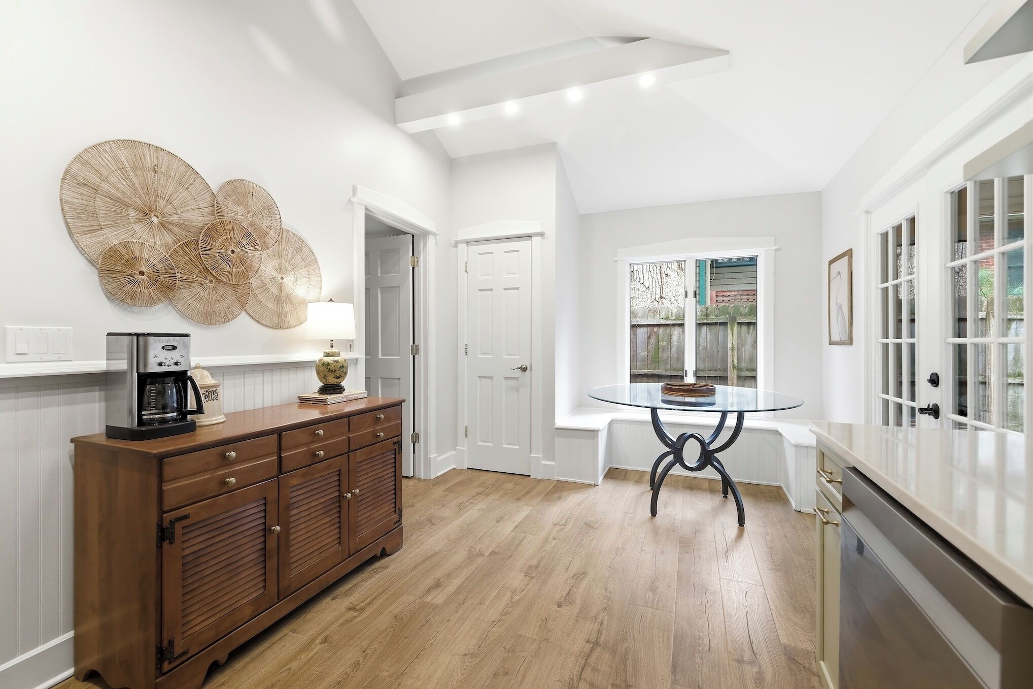 A modern kitchen with a wooden cabinet, a round table, and a decorative wall piece.