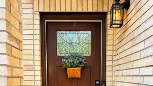 A brown door with a window above it, a basket with flowers, a doorbell, and a 'HOME' mat. - Family Retreat Near Randolph AFB, Patio & Comfort (Converse)