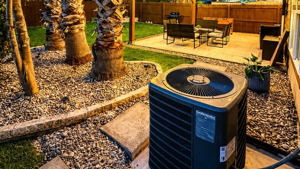 An outdoor patio with a covered seating area, a central air conditioning unit, and a decorative tree wrapped in leaves. - Family Retreat Near Randolph AFB, Patio & Comfort (Converse)