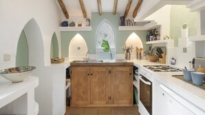 A modern kitchen with wooden cabinets, a central island, and a built-in oven.