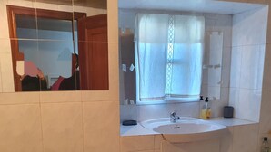 A bathroom with a sink, mirror, and window with curtains.