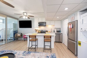 A modern kitchen with a central island, stainless steel appliances, and a ceiling fan. - Walk-Out to Sand - Oceanfront Condo (Ocean City)