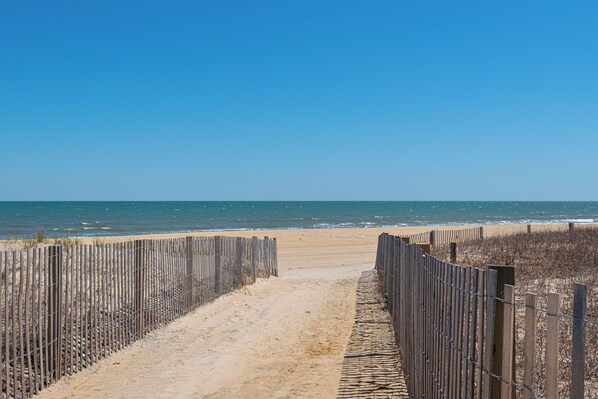 A sandy beach path leading to the ocean, bordered by wooden fences. - Walk-Out to Sand - Oceanfront Condo (Ocean City)