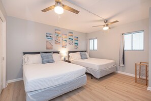 A bedroom with two beds, ceiling fans, artwork on the wall, and a window. - Walk-Out to Sand - Oceanfront Condo (Ocean City)