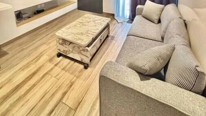 Una sala de estar moderna con un televisor de pantalla plana, un sofá, una mesa de centro y una puerta corredera.