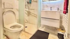 Un baño moderno con inodoro, cabina de ducha, tocador y espejo.