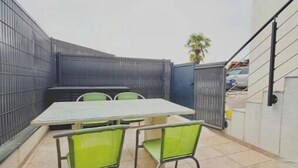 Un patio con mesa y sillas, una escalera y una valla de metal.