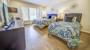 Ein Schlafzimmer mit zwei Betten, einem Schreibtisch und einem Fenster mit Jalousien.