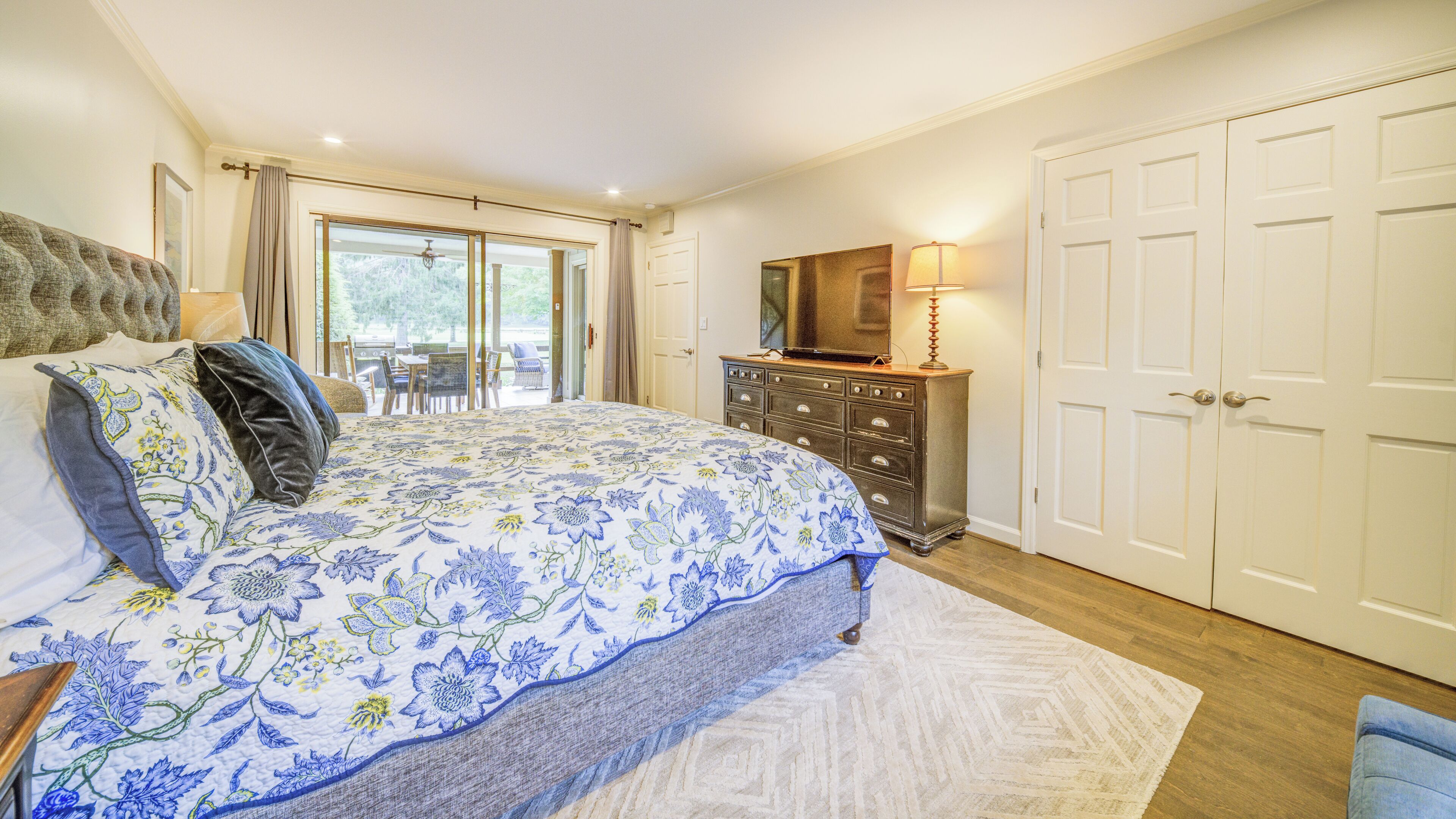A bedroom with a bed, dresser, and a sliding glass door leading to a patio.