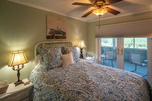 Ein Schlafzimmer mit einem Bett, zwei Nachttischlampen, einem Deckenventilator und Blick auf eine Terrasse.