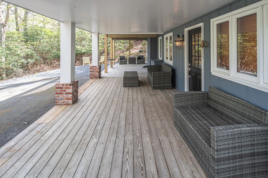 A covered porch with a wooden deck, wicker furniture, and a brick fireplace.