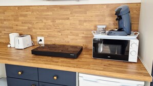A kitchenette with a coffee maker, toaster, and microwave on a wooden countertop.