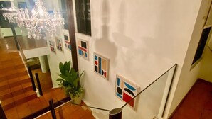 A staircase with a glass railing, a chandelier, and abstract wall art. - Villa in Playacar with a view of the golf course—5-minute walk to the beach and 5th Avenue (Playa del Carmen)