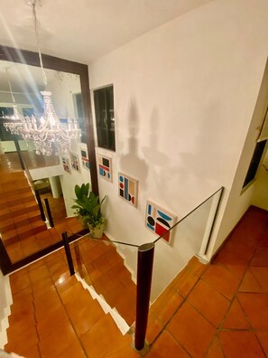 A staircase with a glass railing, a chandelier, and abstract wall art. - Villa in Playacar with a view of the golf course—5-minute walk to the beach and 5th Avenue (Playa del Carmen)