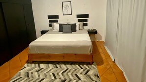 A bedroom with a bed, a wall-mounted air conditioner, a framed picture, and a patterned rug. - Villa in Playacar with a view of the golf course—5-minute walk to the beach and 5th Avenue (Playa del Carmen)