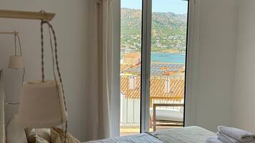 Un dormitorio con cama, una lámpara colgante, vistas a un balcón con paneles solares y una ventana con cortinas.