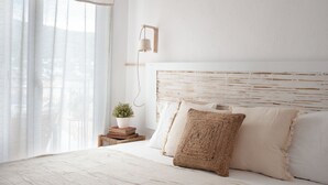 A bedroom with a bed, a bedside table with a plant, and a wall-mounted lamp.