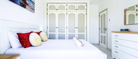 A bedroom with a bed, a nightstand, a dresser, a mirror, and a painting on the wall.