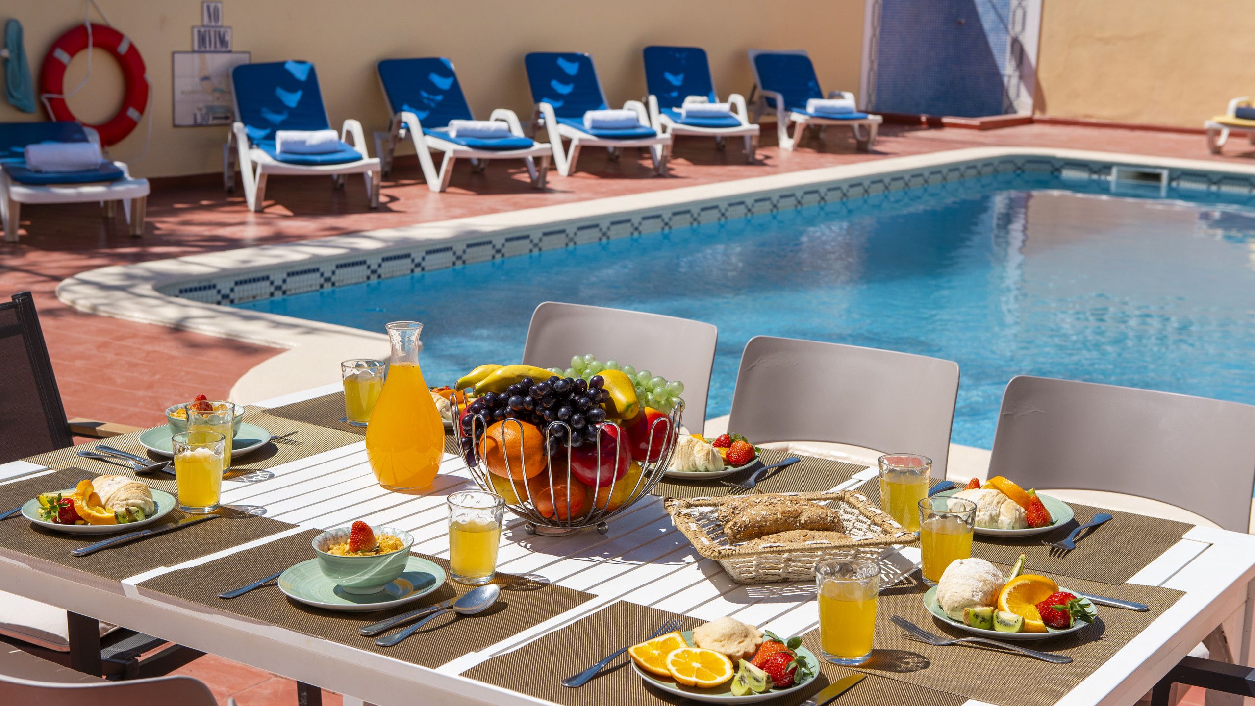 Ein Essbereich am Pool mit Tisch, Stühlen und Obstschale.