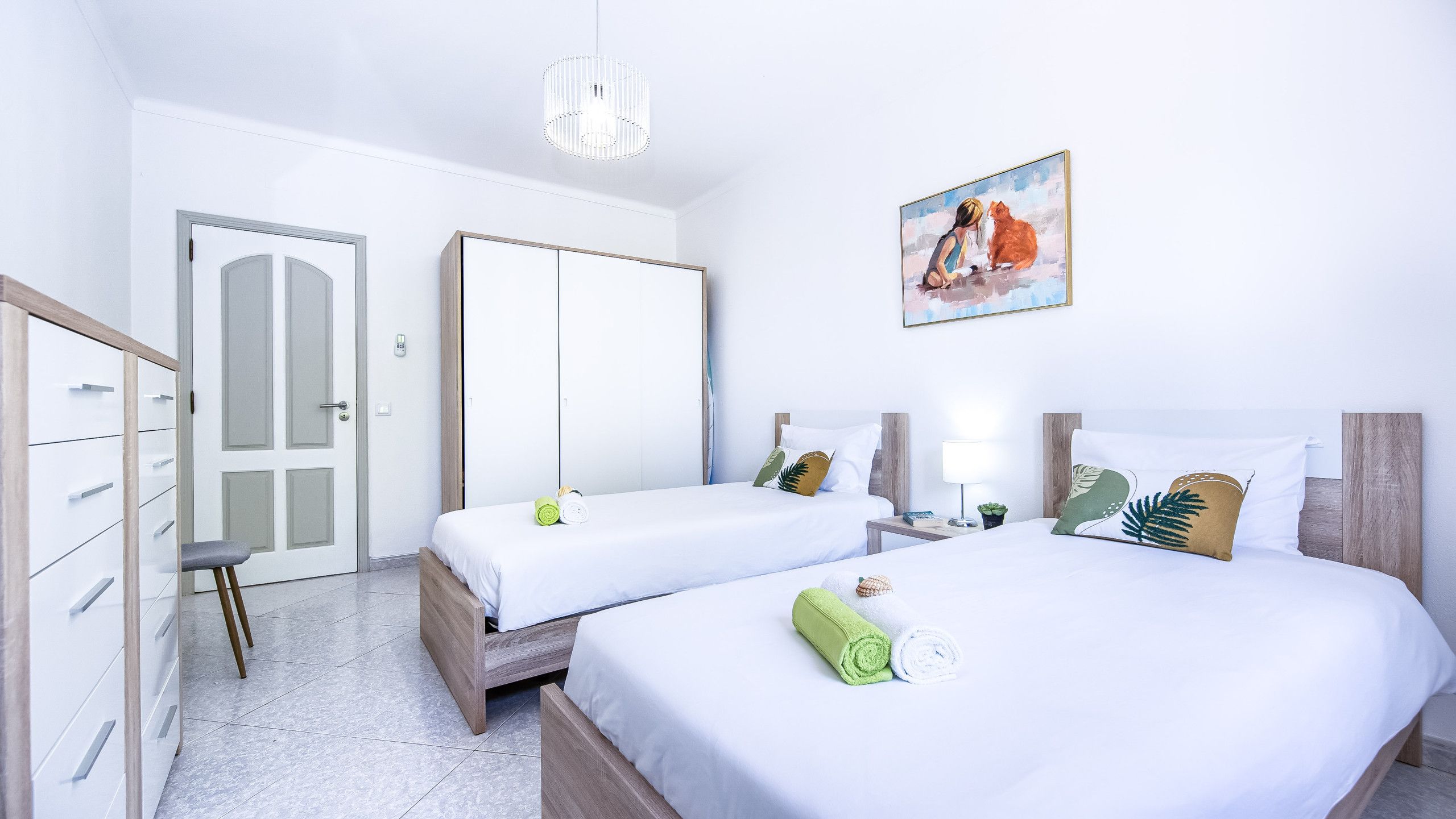 Une chambre d’hôtel avec deux lits, une armoire, un bureau et un tableau au mur.
