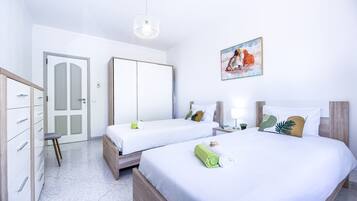 Une chambre d’hôtel avec deux lits, une armoire, un bureau et un tableau au mur.