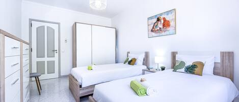 Une chambre d’hôtel avec deux lits, une armoire, un bureau et un tableau au mur.